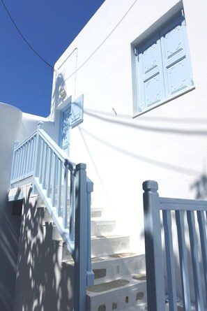 Un bâtiment blanc agrémenté de touches de bleu, notamment une fenêtre et un escalier.