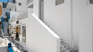 A narrow street with white buildings, a staircase, and a blue bench. - Apartment 'Le Coq' with Balcony, Wi-Fi and Air Conditioning (Mykonos)