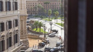 A view of a city street with buildings, palm trees, and a monument. - Venustas Hotel (Rome)
