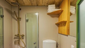 A bathroom with a wooden ceiling, a glass shower enclosure, a toilet, and a sink.