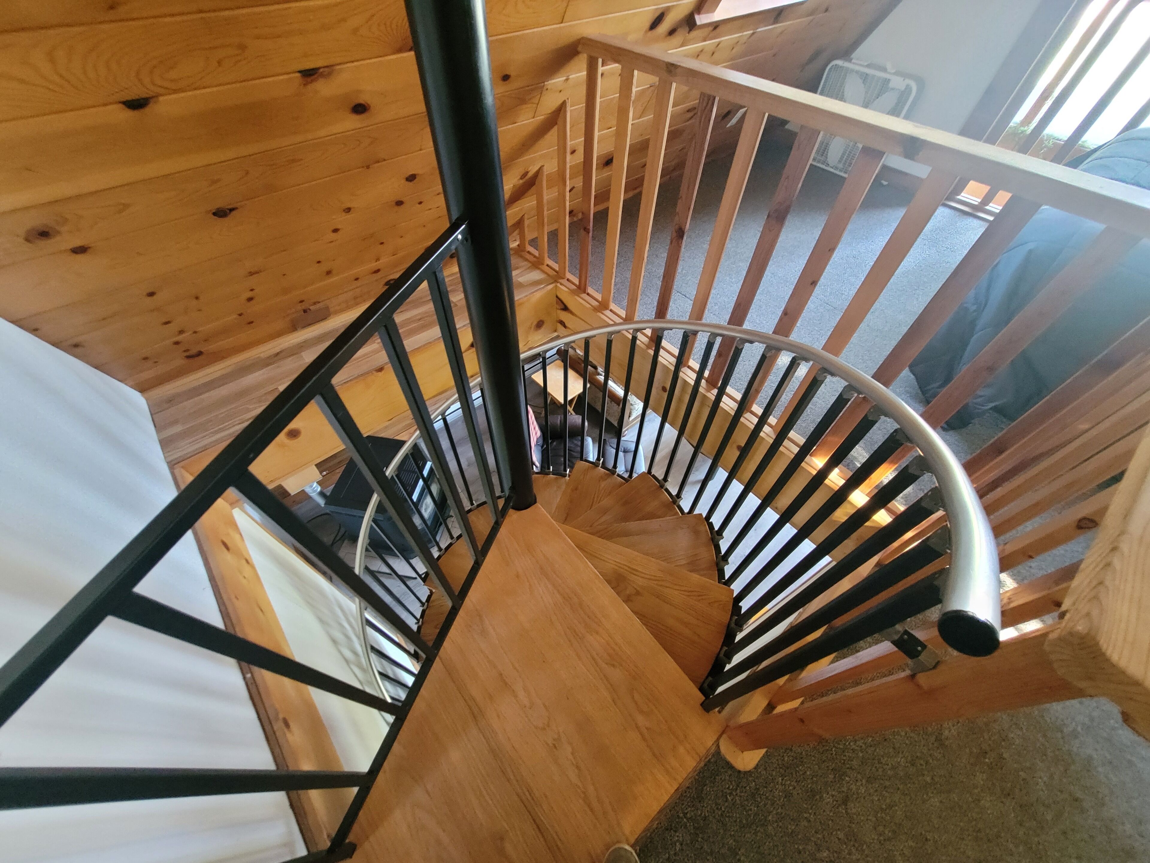 Eine Holzspirale mit Metallgeländern, die zu einer oberen Etage führt.