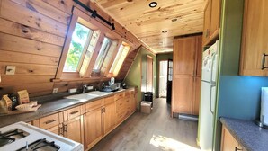 A kitchen with wooden cabinets, a stove, and a sink. - A Frame cabin with a short stroll to a gorgeous sandy beach! (Beaver Island)
