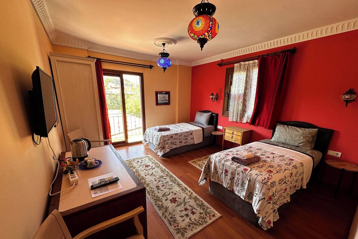 A bedroom with two beds, a desk, a chair, a coffee maker, and a television.