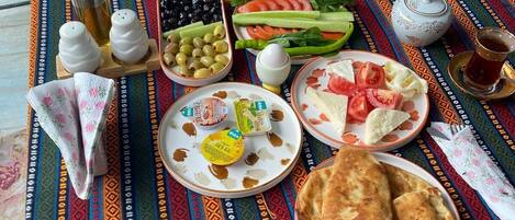 A table set with various dishes, including flatbreads, salads, and a teapot.