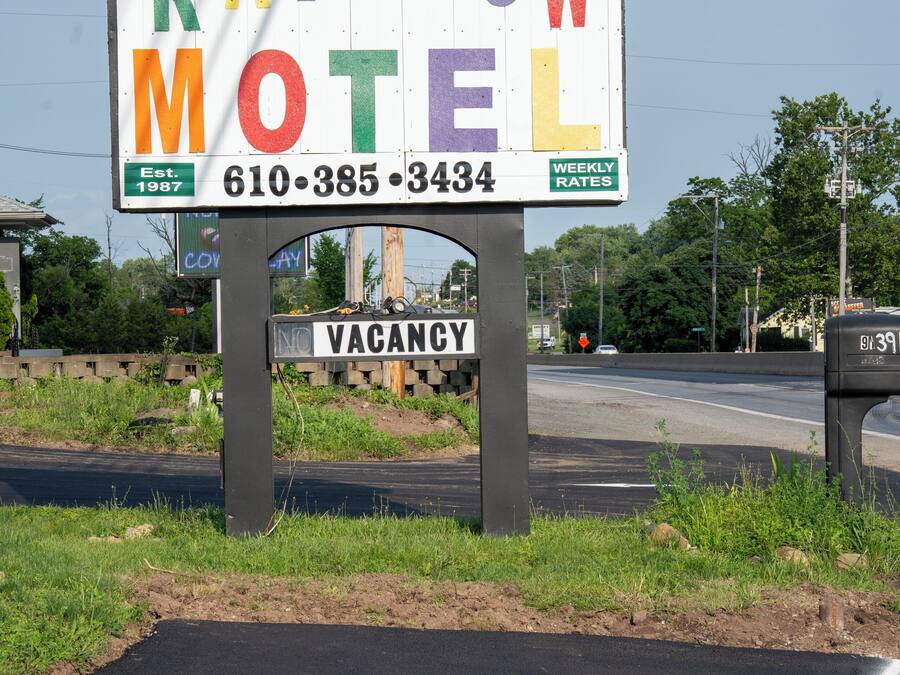 A motel sign with the name 'Rainbow Motel' and a contact number.