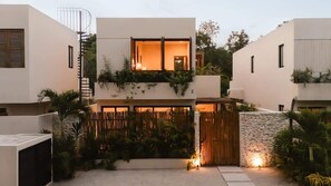A modern two-story house with a balcony, a wooden fence, and a stone wall.
