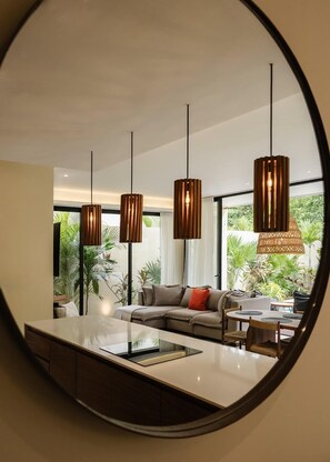 A modern living room with a large mirror, a sofa, a coffee table, and hanging pendant lights.