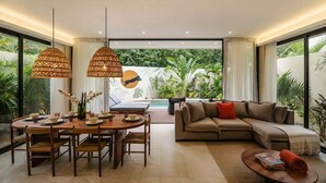A modern living room with a dining area, a sofa, and a pool view.