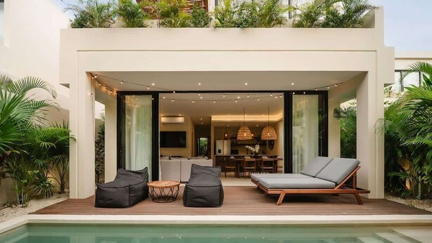 A modern house with a pool, outdoor seating, and a dining area.