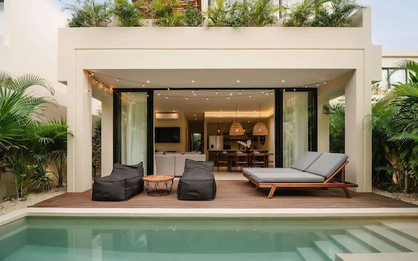 A modern house with a pool, outdoor seating, and a dining area.