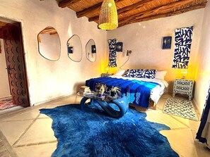 Une chambre à coucher avec un lit, un tapis bleu, un miroir et un mur orné de motifs décoratifs.