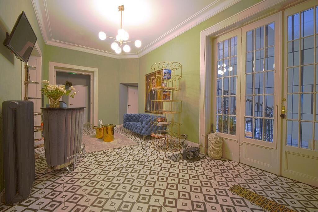 A room with patterned flooring, a blue sofa, a television, and a door with glass panels.