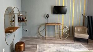 Ένα μοντέρνο σαλόνι με μια τηλεόραση τοποθετημένη στον τοίχο, έναν καναπέ, ένα τραπεζάκι σαλονιού και ένα διακοσμητικό μεταλλικό ράφι.
