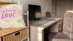 A cozy room with a wooden desk, a comfortable chair, a television, and a wicker basket. - Quiet, spacious country house 1 hour from Disney land. 1 h00 from Paris. (Hautevesnes)