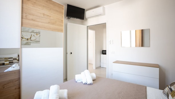 A modern hotel room with a bed, a bedside table, a TV, and a bathroom visible through an open door. - Casa vacanze D&G - Marina di Ragusa (Marina di Ragusa)