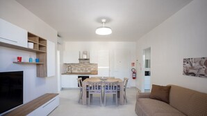 A modern living room with a TV, a sofa, and a dining area with a table and chairs. - Casa vacanze D&G - Marina di Ragusa (Marina di Ragusa)