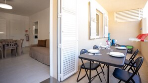 A dining area with a table set for four, a sofa, and a kitchen area visible in the background. - Casa vacanze D&G - Marina di Ragusa (Marina di Ragusa)