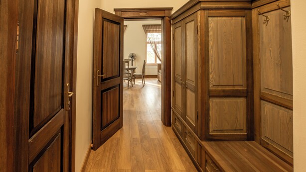A hallway with wooden doors and a wooden bench.