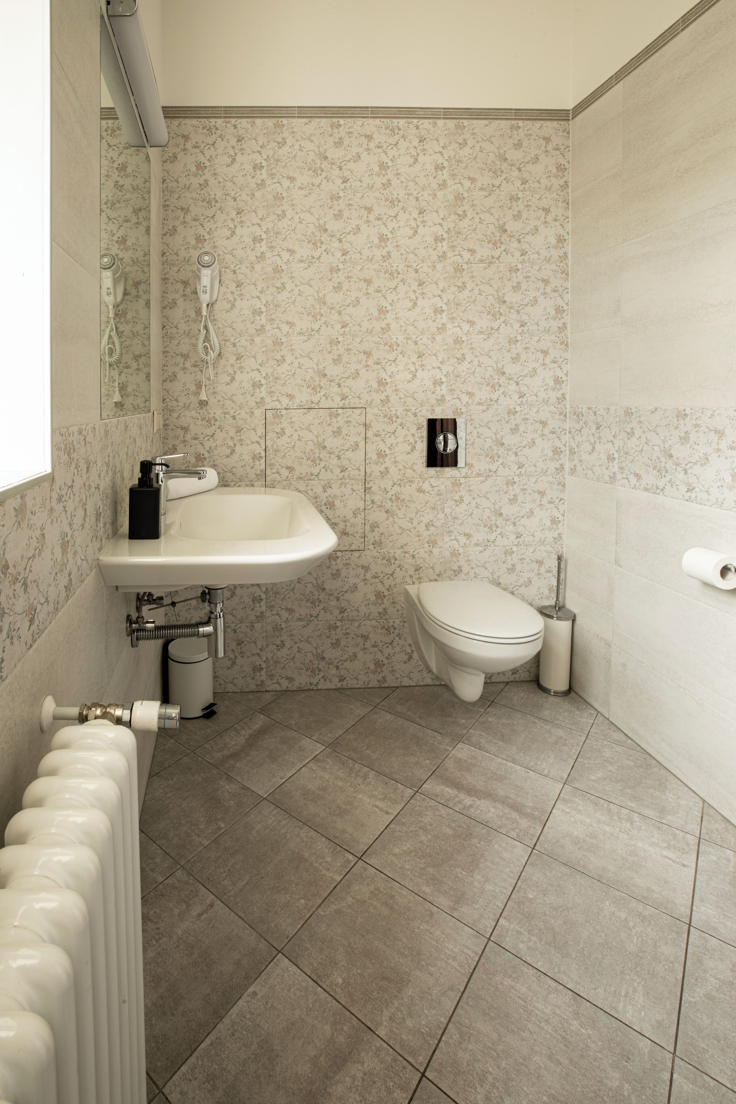 A bathroom with a white sink, toilet, and radiator.