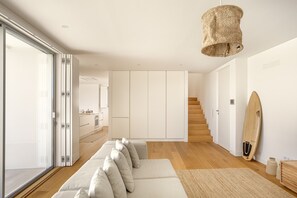 A modern living room with a sofa, a staircase, and a surfboard. - Ericeira Modern & Bright by Homing (Mafra)