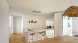 A modern kitchen with a central island, bar stools, and a wooden dining table.