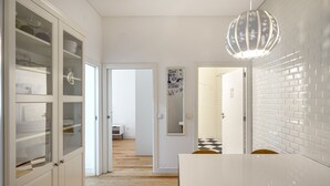 Eine moderne Küche mit weißen Schränken, einer weißen Arbeitsplatte und einer Pendelleuchte.