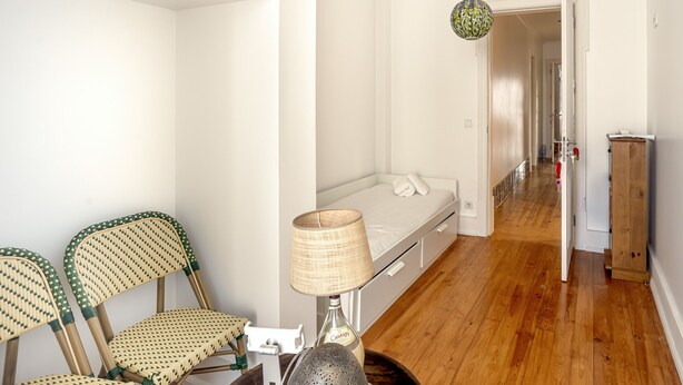Ein Zimmer mit einem Bett, einer Lampe, zwei Korbstühlen und einem Holzboden.