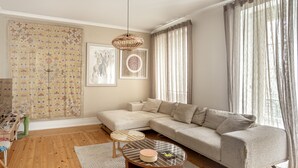 Ein Wohnzimmer mit einer Eckcouch, einem runden Couchtisch, einem kleinen Beistelltisch und einer Pendelleuchte.