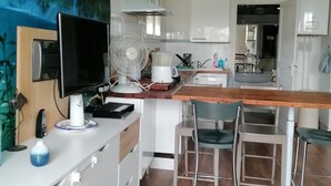A modern kitchen with a wooden dining table, white cabinets, a built-in fan, and a large window.