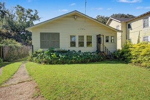 A single-story house with a front yard, a pathway leading to the front door, and a small garden area.