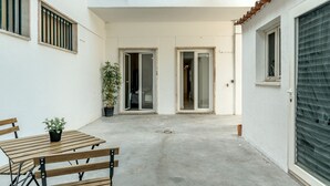 A courtyard with a wooden table and chairs, a potted plant, and a sliding glass door leading to an interior space. - Estrela House III by Homing (Lisbon)