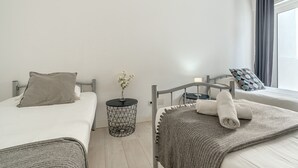 A bedroom with two beds, a bedside table with a vase, and a wall-mounted sign. - Estrela House III by Homing (Lisbon)