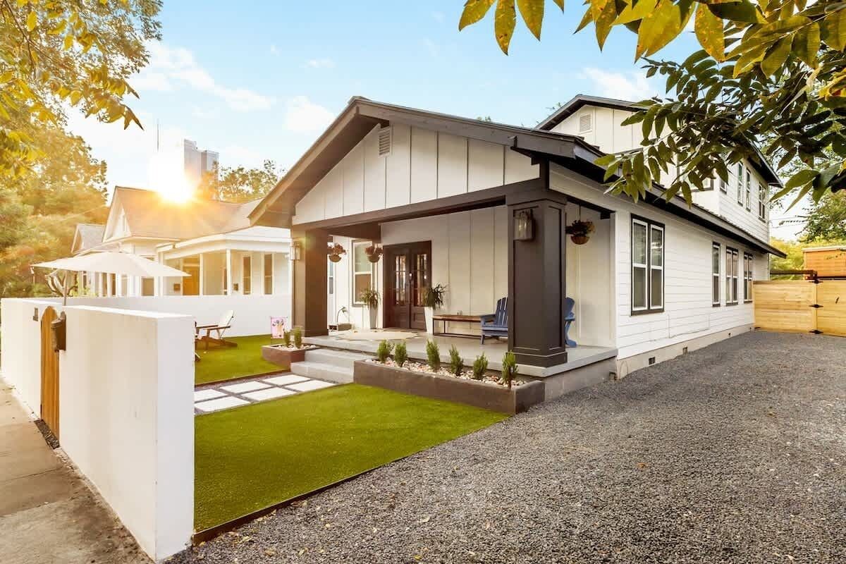 Ett modernt hus med en inglasad veranda, en liten gräsmatta och en grusuppfart.