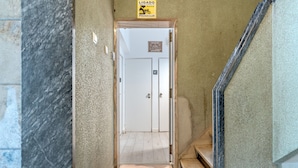 Un couloir menant à des toilettes, avec une pancarte au-dessus de la porte.