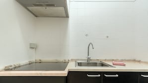 Une cuisine équipée d’un évier, de meubles de rangement noirs et d’un plan de travail en marbre.