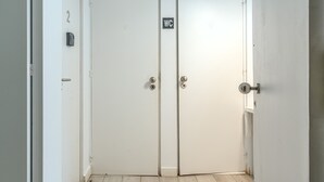 A pair of white doors with a WC sign, a number '2' sign, and a doorbell. - Estrela House IV by Homing (Lisbon)