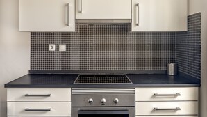 Una cocina con armarios blancos, salpicadero de azulejos negros y una campana extractora de acero inoxidable.