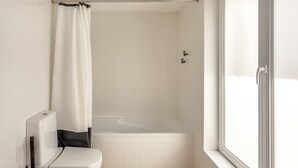 Un baño con bañera, inodoro y ventana.
