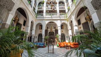 An interior courtyard with ornate arches, a central seating area, and a view of the upper floors.