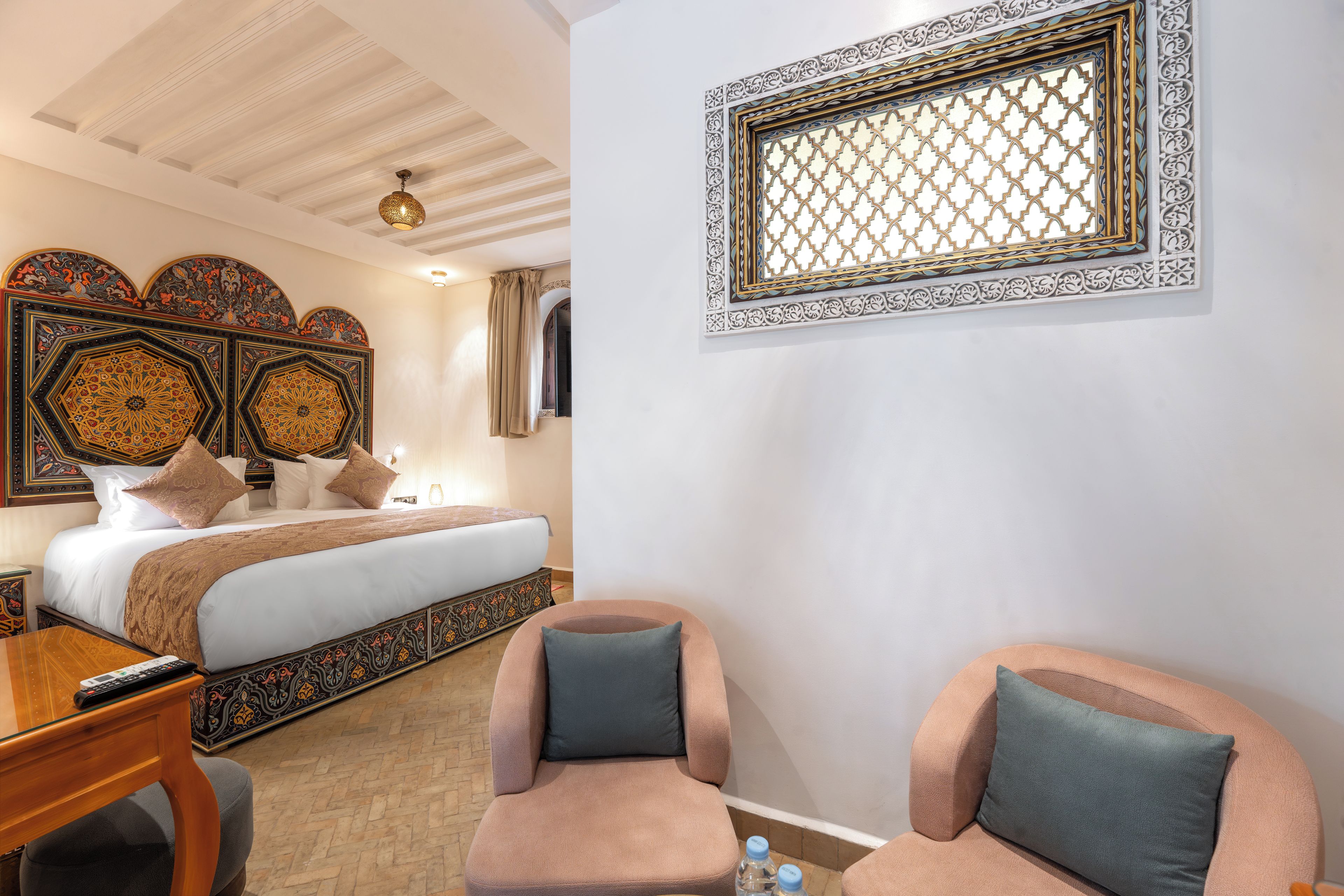 Een hotelkamer met een bed, twee stoelen, een bureau en een decoratief paneel aan de muur.