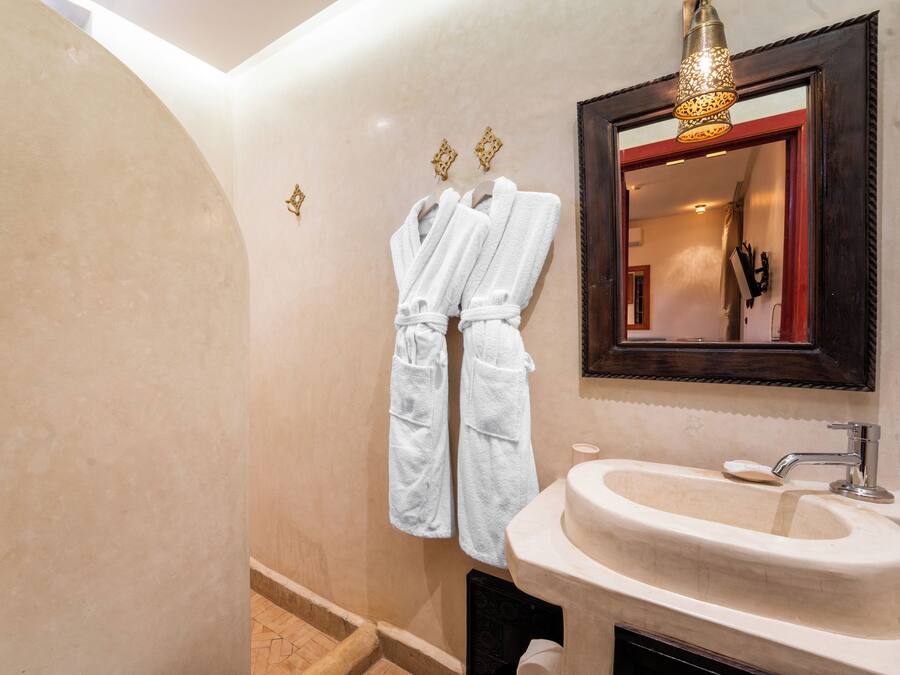 A bathroom with a sink, mirror, and two white towels hanging on hooks.