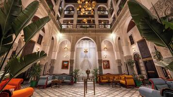 A lobby with a high ceiling, ornate arches, and a central chandelier.
