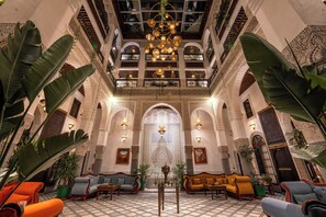 A lobby with a high ceiling, ornate arches, and a central chandelier. - Riad Joy (Fes)