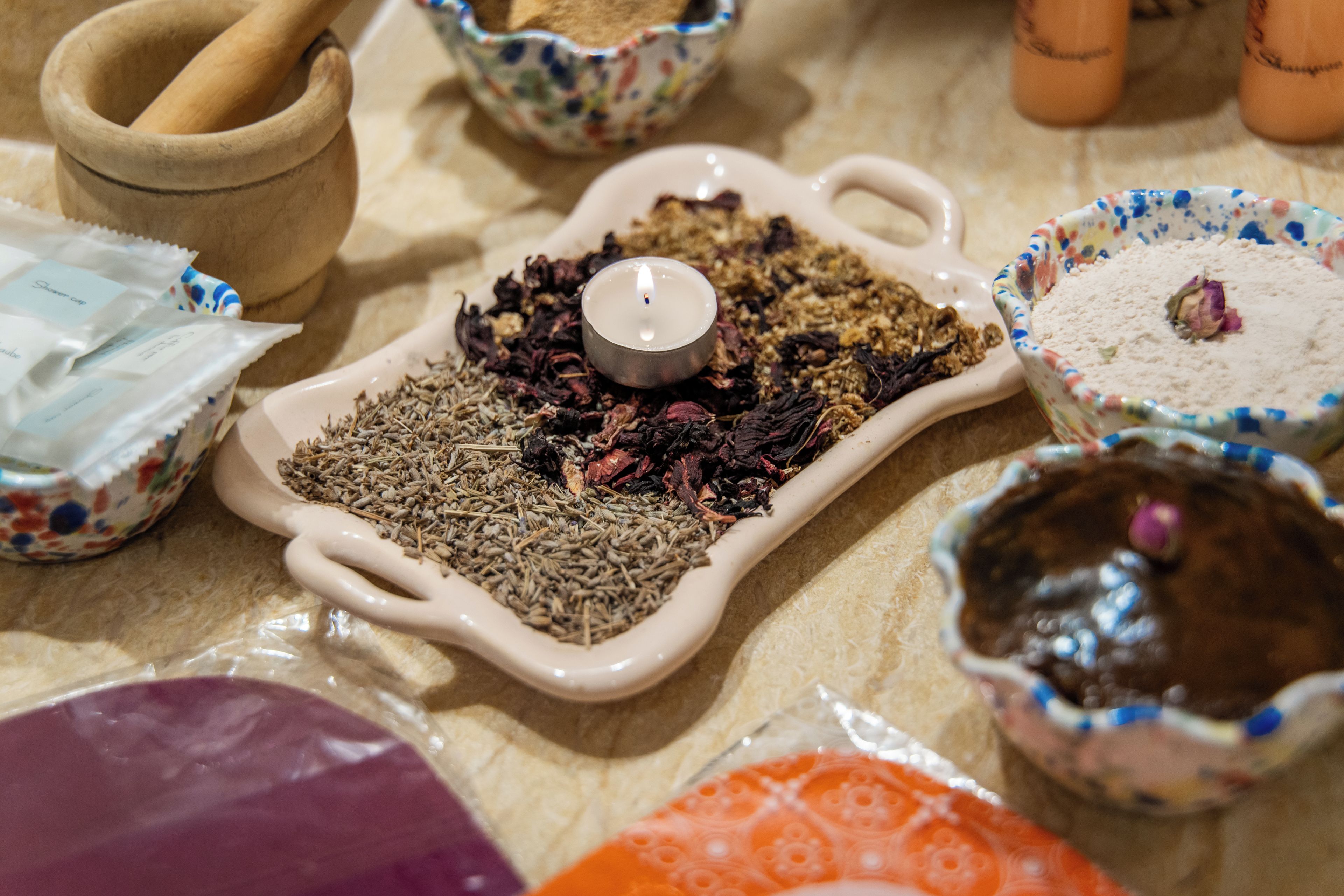 A variety of dried herbs and spices in ceramic containers on a countertop.
