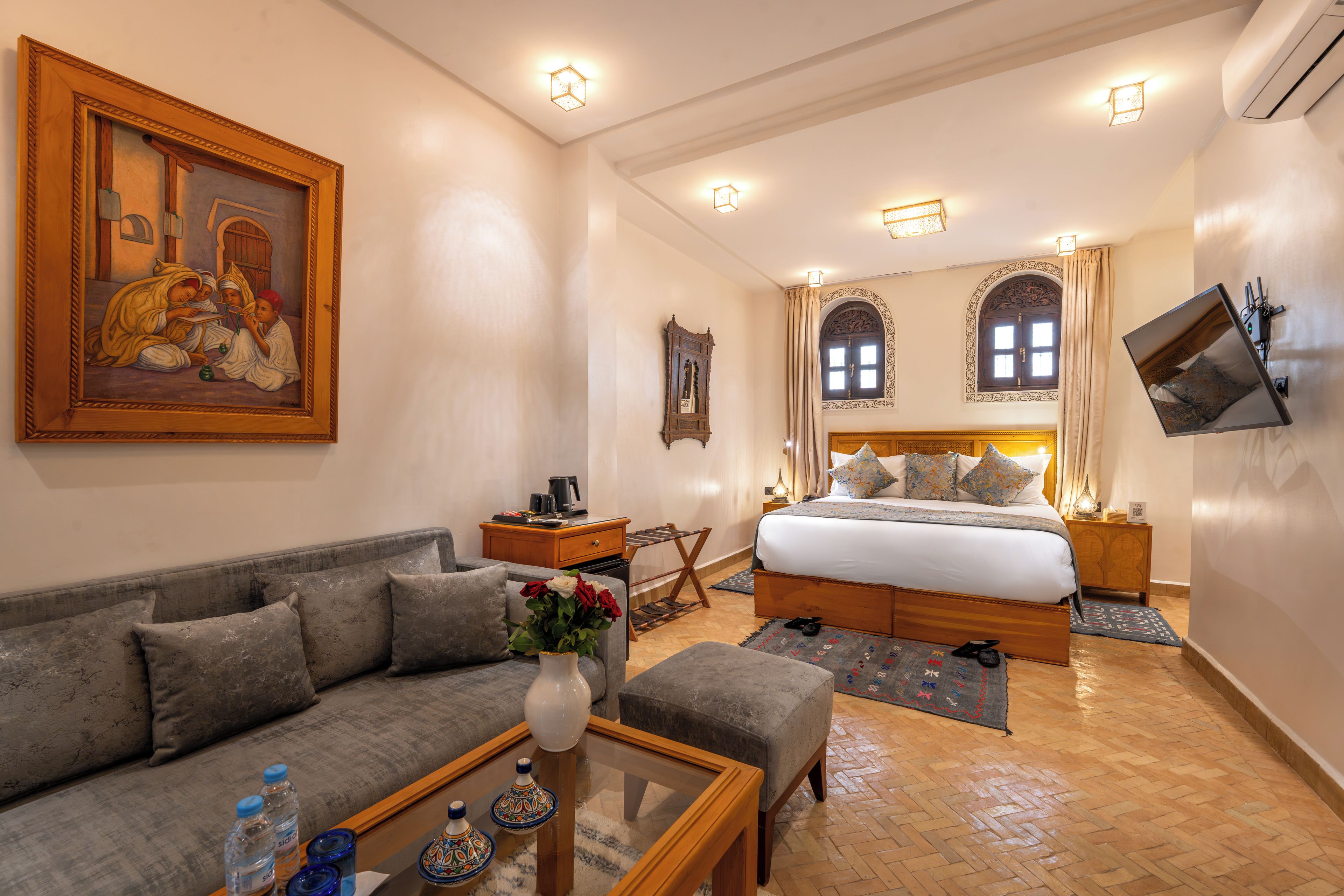 A hotel room with a bed, a sofa, a coffee table, and a painting on the wall.