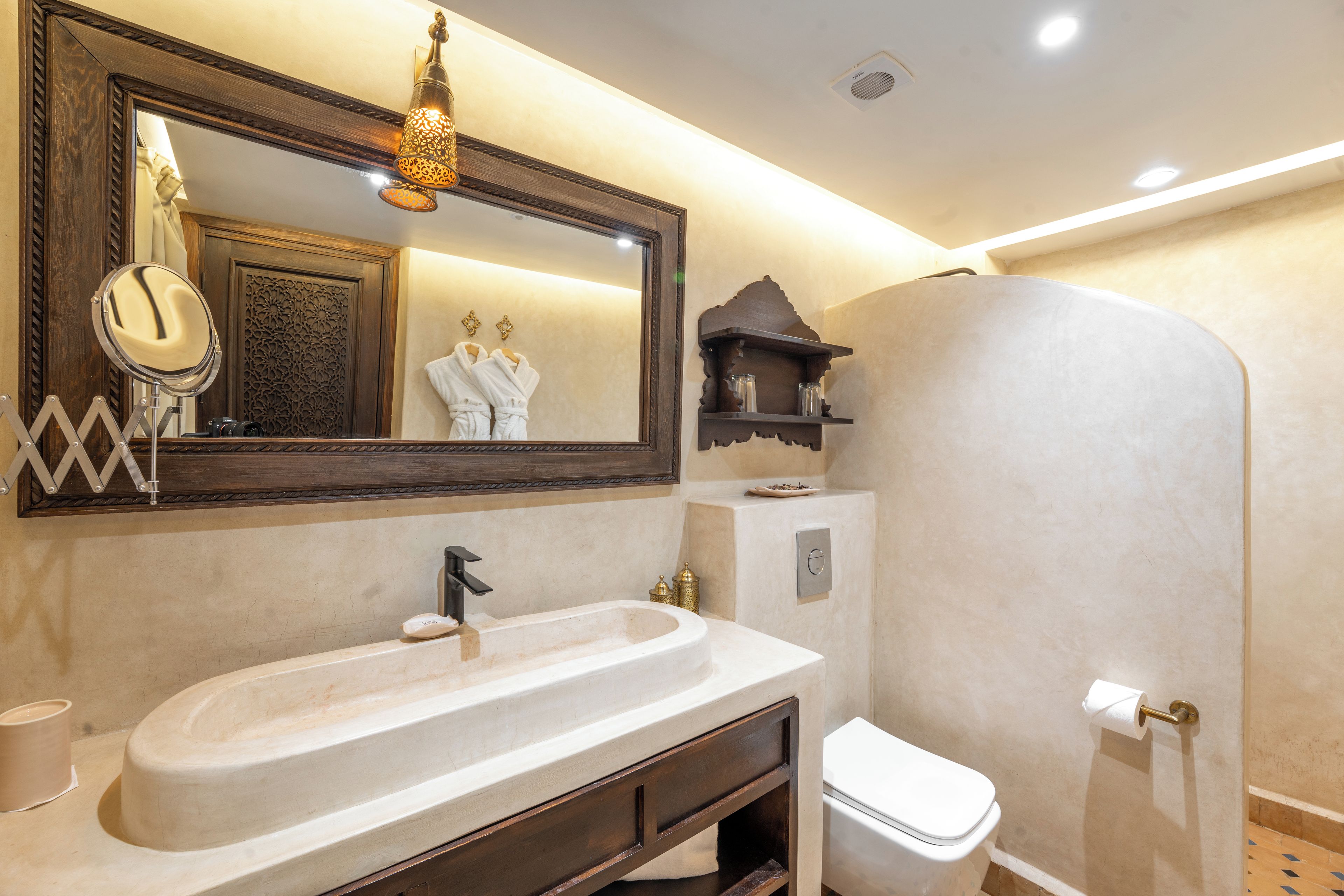 Un baño con un espejo grande, lavamanos, inodoro y zona de ducha.