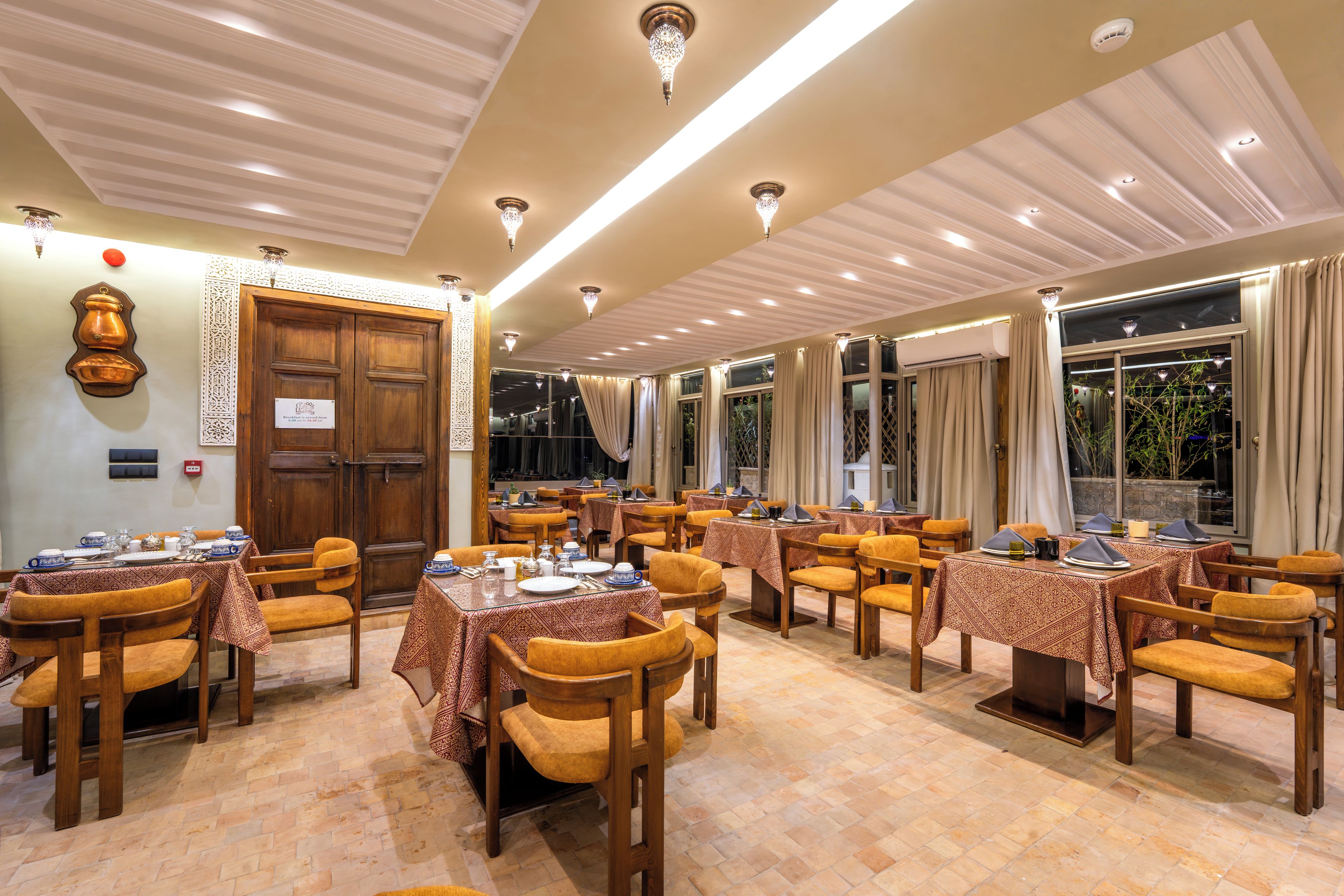 Comedor de hotel con varias mesas, sillas y una pared decorativa.
