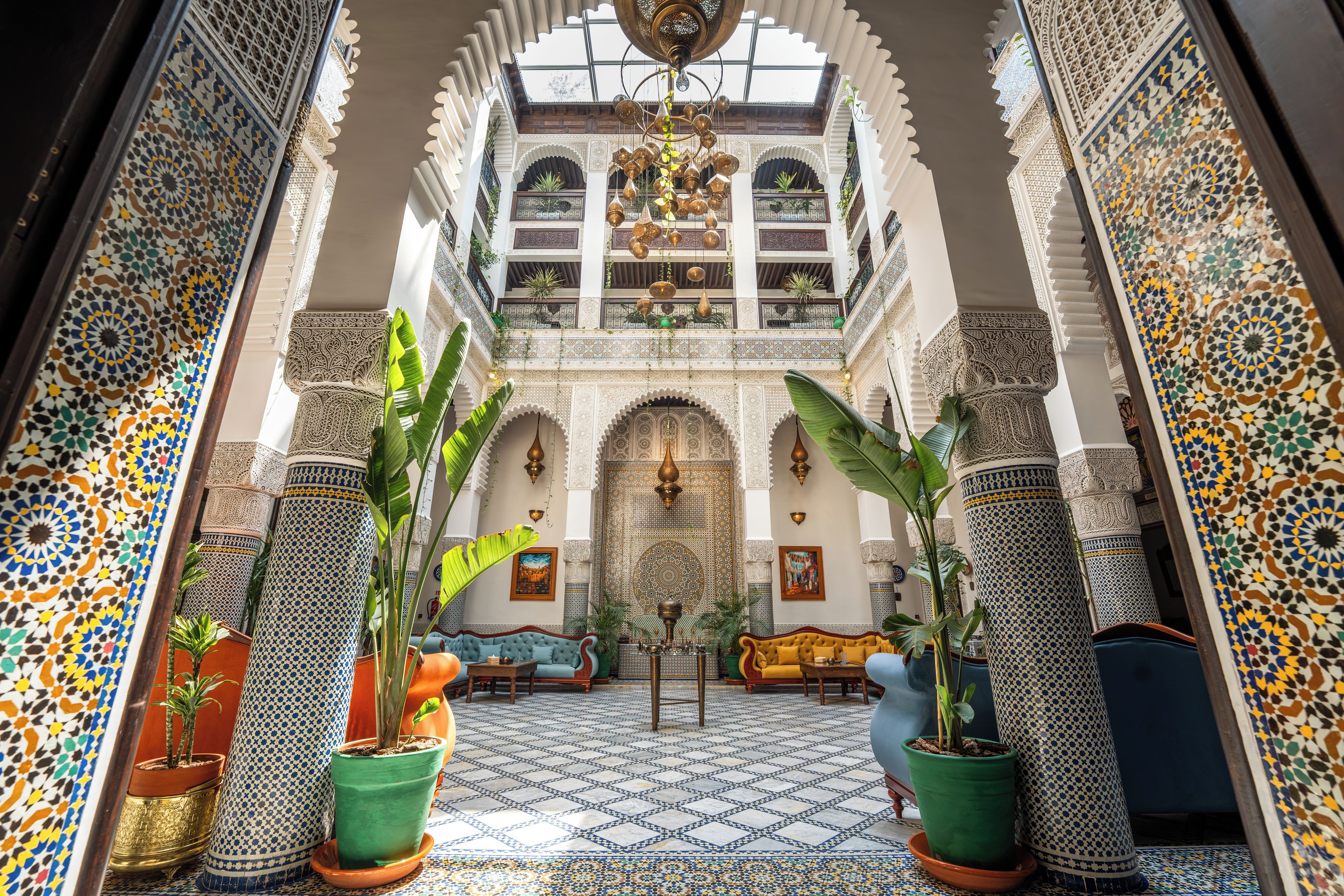An interior with a high ceiling, ornate arches, and patterned floor tiles.