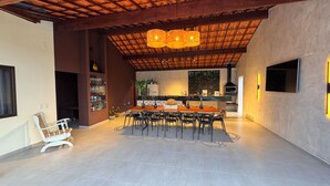 Uma sala de jantar ampla com uma mesa comprida e cadeiras, uma cozinha com forno embutido e uma janela grande que oferece iluminação natural.