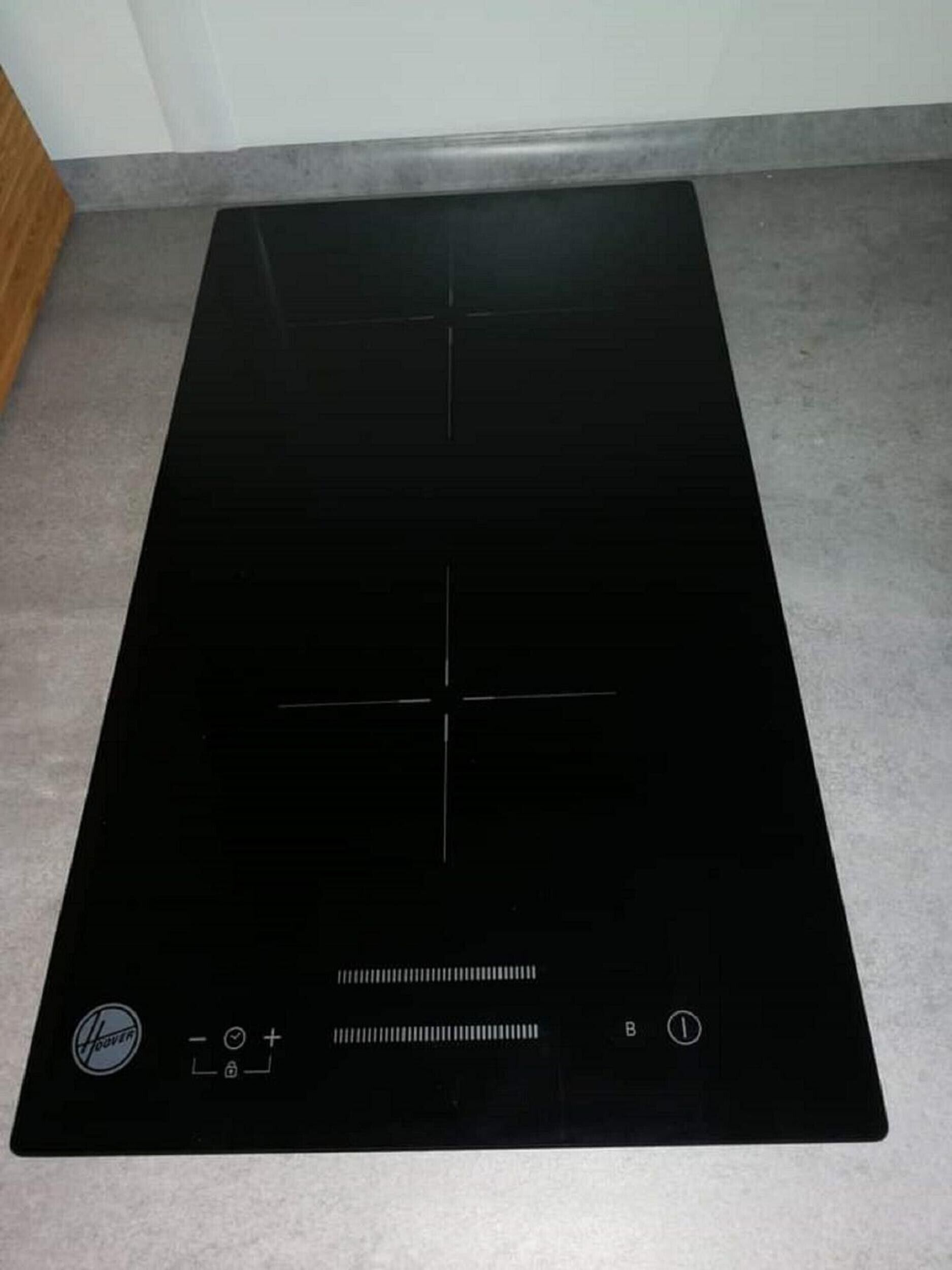 A black induction cooktop with control buttons and a power switch.